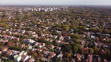 Aerial-flyover-rural-residential-area-in-Buenos-Aires-with-green-trees-and-block-complex-in-background