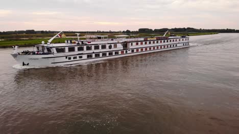 Luftaufnahme-Des-Hafens-Neben-Dem-Olympia-Kreuzfahrtschiff,-Das-An-Einem-Anderen-Schiff-Auf-Dem-Fluss-Noord-Vorbeifährt