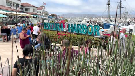 Tourists-local-residents-enjoy-the-walkway-and-promenade-at-Ventura-Beach,-California---sliding-establishing-shot