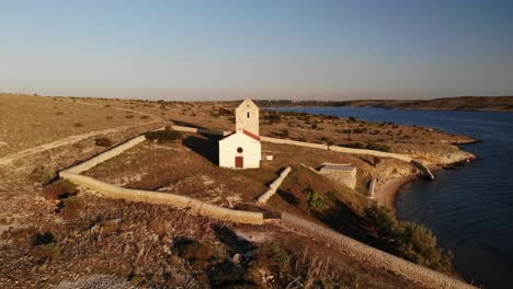 Hermosa-Iglesia-Tradicional-De-Una-Pequeña-Isla-En-El-Adriático,-Vista-Aérea-Volando-Hacia-Atrás