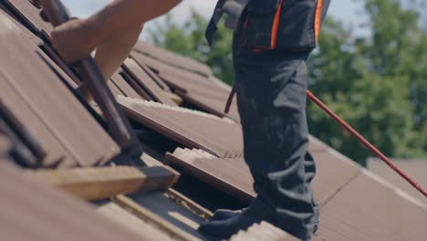 Roofer-working-on-roof-using-safety-rope,-removing-tiles