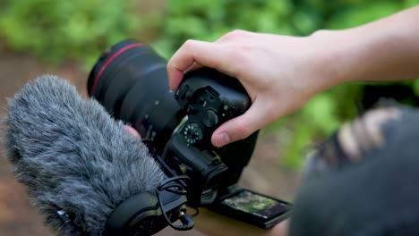 Close-up-of-professional-mirrorless-camera-with-microphone-shooting-photos-in-a-sunny-outdoor-forest