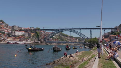 Tourists-sitting-and-taking-photos-of-Ponte-Luis-Bridge-on-bright-sunny-european-summer-day-with-River-Duoro-and-Ribeira,-Porto,-Portugal