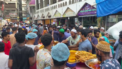 Aufnahme-Aus-Einem-Hohen-Winkel-über-Einheimische,-Die-Vor-Dem-Kauf-Auf-Einem-Alten,-Belebten-Traditionellen-Straßen-Iftar-Lebensmittelmarkt-In-Dhaka,-Bangladesch,-Verhandeln,-Der-Auf-Allen-Seiten-Von-Häusern-Umgeben-Ist