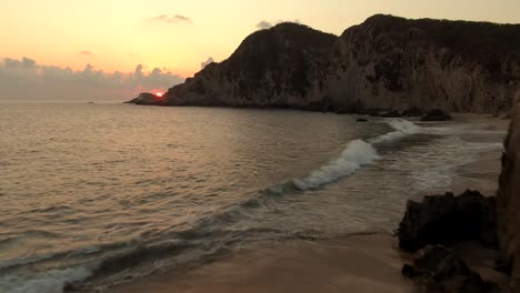 Tranquilo-Paisaje-De-Puesta-De-Sol-En-La-Playa-De-Maruata-Con-Turistas-En-La-Orilla-En-Michoacán,-México---Retroceso-Aéreo