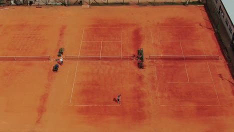 Man-painting-line-on-tennis-court-preparing-it-for-training-game,Krakow-Poland,-aerial-view