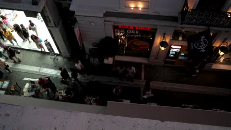 Aerial-evening-view-of-Adrianou-Street-in-Athens,-with-Hard-Rock-Cafe-flag-waving-and-people-walking-around