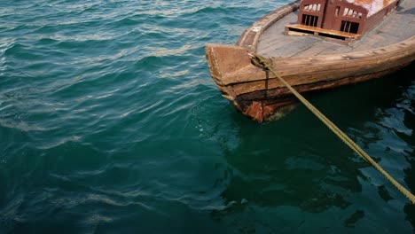 Traditionelles-Ikonisches-Abra-Boot-Im-Berühmten-Dubai-Creek,-Das-Am-Dock-Festgemacht-Ist-Und-Sich-In-4K-Auflösung-Weiter-Entfernt
