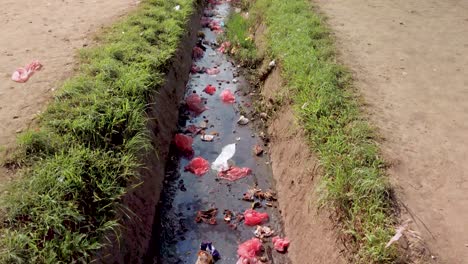 Plastikmüll-Im-Wasser,-Schwenk-Nach-Oben,-Um-Den-Blick-Auf-Die-Straße-Mit-Müllbergen-Freizugeben