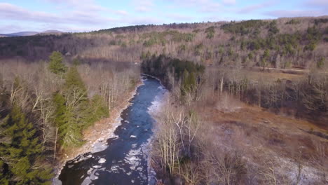 Aerial-drone-footage-approaching-a-winter-cabin-on-a-river-in-upstate-new-york