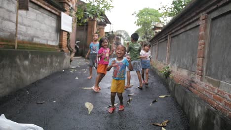 Eine-Kleine-Gruppe-Balinesischer-Kinder-In-Zeitlupe-Springt,-Lacht-Und-Grüßt-Und-Blickt-Aufgeregt-In-Die-Kamera
