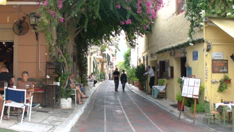 Turistas-Caminando-En-Una-Calle-Angosta-En-La-Tradicional-Ciudad-De-Plaka-Cerca-De-La-Acrópolis-En-Atenas,-Grecia