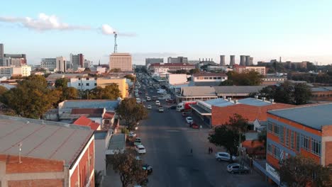 A-pull-down-drone-shot-of-Bulawayo,-Zimbabwe's-city-area-at-sunset