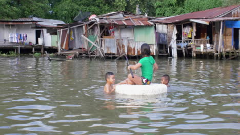 Niños-Tailandeses-Jugando-En-El-Agua-Frente-A-Las-Casas-Sobre-El-Agua