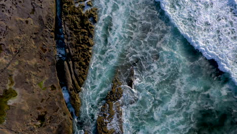 Drone-descending-over-powerful-waves-coming-ashore-at-a-reef-in-La-Jolla,-California,-near-San-Diego