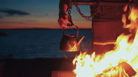 Man-hanging-kettle-over-fireplace-by-the-sea