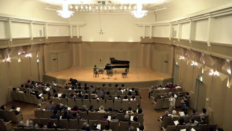 Spectators-sitting-at-a-concert-hall-with-a-program-in-their-hands