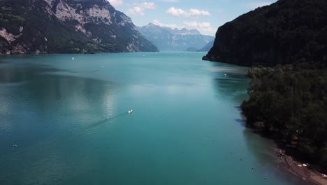 Aerial,-drone-rising-shot-of-sailboats-in-a-beautiful-fjord-lake-in-Switzerland-while-summer