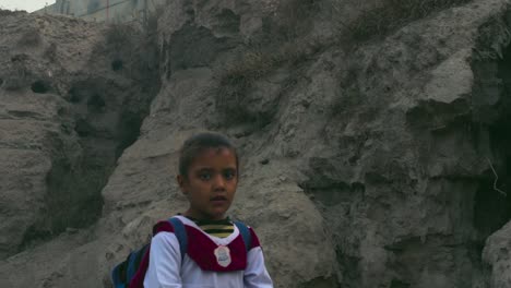 Pakistanische-Schulkinder-Im-Ländlichen-Gebiet-In-Weißer-Uniform-Auf-Der-Straße,-Ein-Junge-Und-Ein-Mädchen,-Ein-Abwasserrohr,-Das-Von-Der-Unterentwickelten-Hügeligen-Straße-Ausgeht