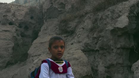 Pakistani-rural-area-school-children-in-the-street-in-white-uniform,-A-boy-and-a-girl,-A-sewerage-pipe-going-from-the-under-constructed-hilly-street