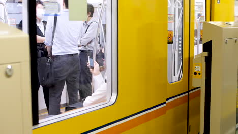 Static-shot,-of-people-inside-a-yellow-Ginza-line,-subway,-at-a-metro-station,-in-Japan