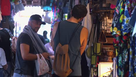 Männliche-Touristen-Probieren-Kleidung-Auf-Dem-Markt-Aus