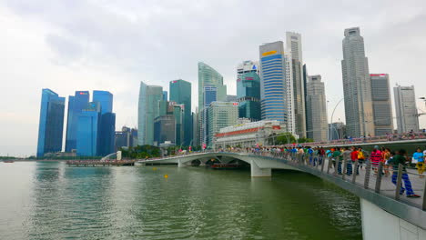 SIngapore---Circa-Wide-static-time-lapse-of-the-Singapore-city-skyline-with-people-walking-over-a-bridge