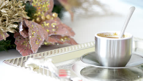 Cup-of-cappuccino-with-spoon-on-silver-tray-in-kitchen-decorated-for-Christmas