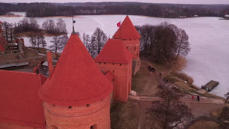 AERIAL:-Rotating-Shot-of-Gotic-Style-Medieval-Trakai-Island-Castle-Tower-with-Lithuanian-Flag-Waving-on-Top-of-One-of-the-Towers