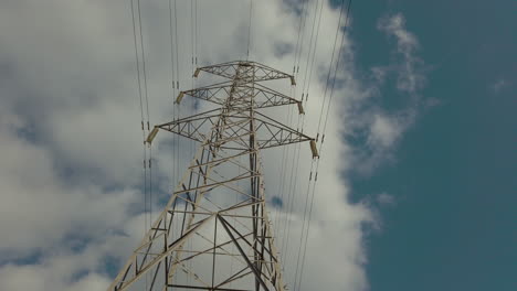 Electricity-pylon-in-the-middle-of-a-farmers-field-with-cables-stretching-across-the-blue-sky-of-the-countryside
