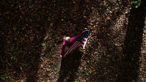 Mirando-Hacia-Abajo-Mientras-Una-Mujer-Gira-Con-Una-Bandera-Estadounidense-En-Un-Bosque