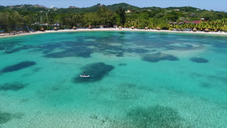 Vista-Aérea-De-Personas-Haciendo-Paddleboarding-Cerca-De-La-Playa-De-Un-Resort-En-El-Mar-Caribe-Hondureño