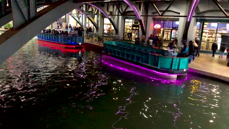 Die-Hellen-Und-Farbenfrohen-Neon-LED-Lichter-Der-Flussboote-Auf-Dem-San-Antonio-Riverwalk,-Deren-Lichter-Auf-Der-Oberfläche-Zu-Tanzen-Scheinen