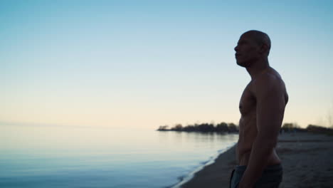 Sportlicher-Mann-Meditiert-Bei-Sonnenuntergang-Am-Strand