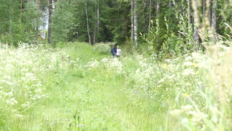 Eight-and-nine-year-old-boys-walking-in-floral-summer-meadow,-SLOW-MOTION