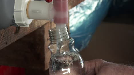 Man-filling-bottles-with-a-cleaning-agent-in-a-micro-industry,-close-up