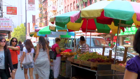 Street-scene-in-Little-Italy,-Manhattan,-people-walking-and-crossing-roads-with-traffic