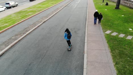 Weiße-Frau,-Die-Auf-Longboard-Die-Straße-Hinunter-In-Montevideo-Uruguay-Skatet