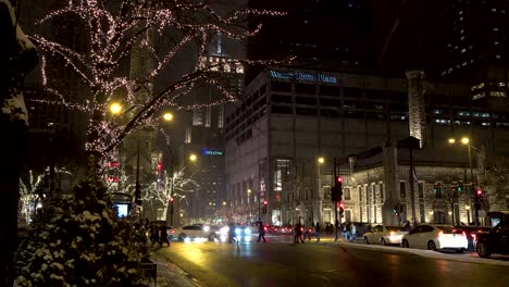 people-walking-across-city-crosswalk-at-night-Chicago-downtown-magnificent-mile-during-Christmas-season-4k-past-historic-water-tower-landmark