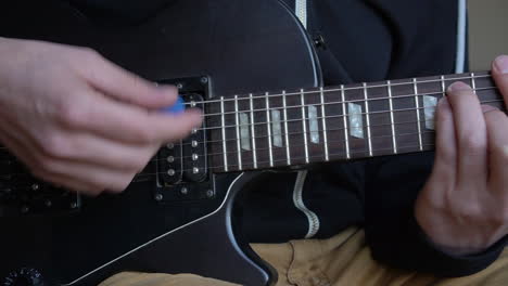 Man-Practising-a-vintage-black-electric-guitar,-rehearsing-chords,-solos-and-octaves-in-a-natural-light-environment.