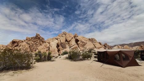 Campsite-with-tent-setup-in-Joshua-Tree-National-Park-in-front-of-a-mountain-of-boulders-in-California