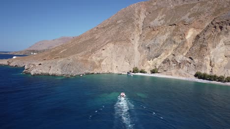 Drone-Follows-Boat-to-A-Beach-Under-Dramatic-Cliffs