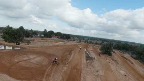 Motocross-riders-jump-and-ride-along-dirt-track-on-cloudy-day