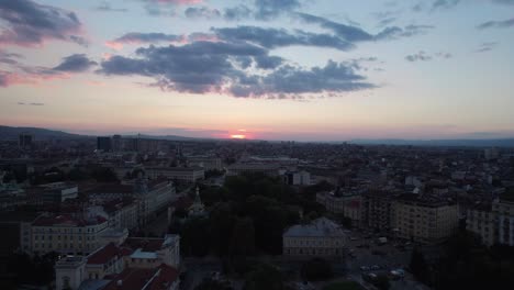 Panning-to-reveal-the-red-sun-setting-behind-horizon-in-Sofia,-aerial