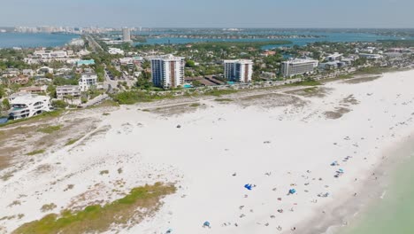 Multi-angle-aerial-view-of-people-on-a-Florida-beach-with-city-skyline-in-the-background