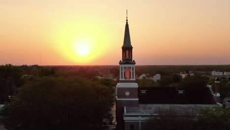 A-parallax-aerial-establishing-shot-sunset-view-of-a-church-steeple-in-Ocala,-Florida