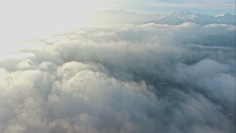 White-fluffy-clouds-above-mountain-range,-aerial-drone-high-altitude-view