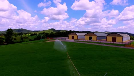 Irrigation-sprinkler-on-an-organic-farm-watering-crops---aerial-flyover
