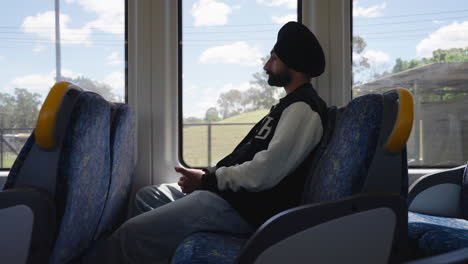 Un-Viajero-Indio-Punjabi-Sikh-Hombre-Sentado-En-Un-Tren-En-Movimiento
