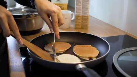 the-close-up-shot-of-a-woman-turning-around-pancakes-in-the-pan-at-home-kitchen,-woman-is-making-breakfast